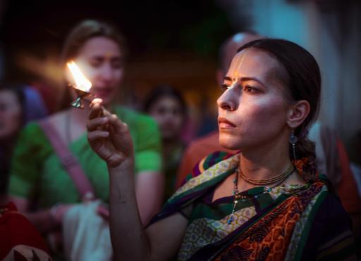 A devotee offering a candle as an offering to the Deities